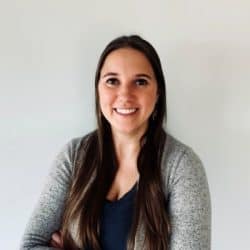 Dr. Tiffany Bullard smiling with arms crossed, wearing a dark top and light gray cardigan, standing in front of a plain light-colored background.